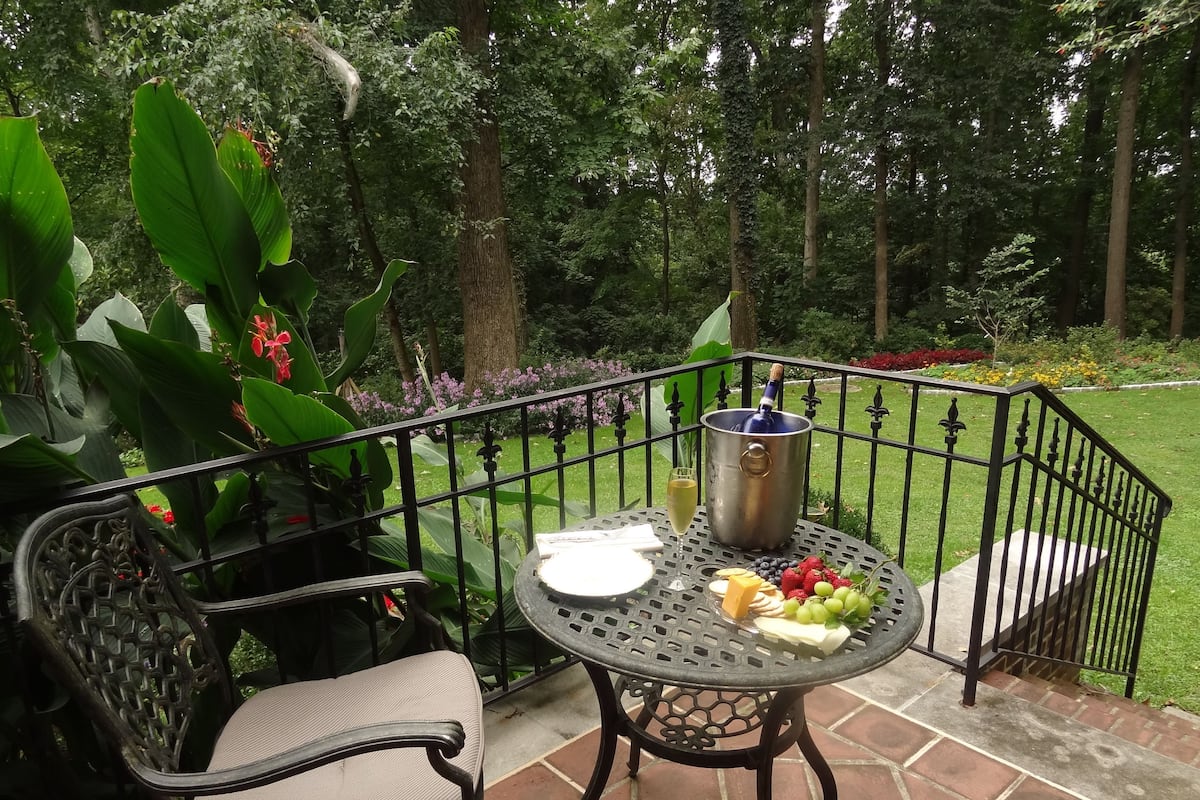 A patio with a table set for a meal, a wine bottle, and a chair.