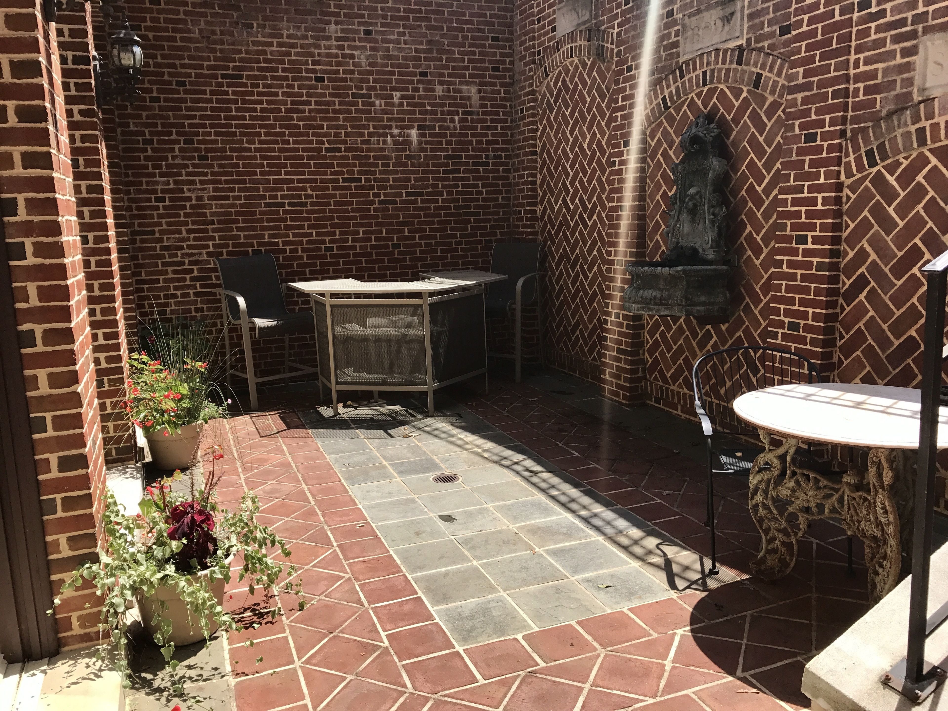 A patio area with a brick wall, a table with chairs, and potted plants.