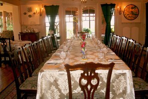 Enjoy a classic dining experience with a beautifully set table, elegant chandelier, and a vase of fresh flowers.