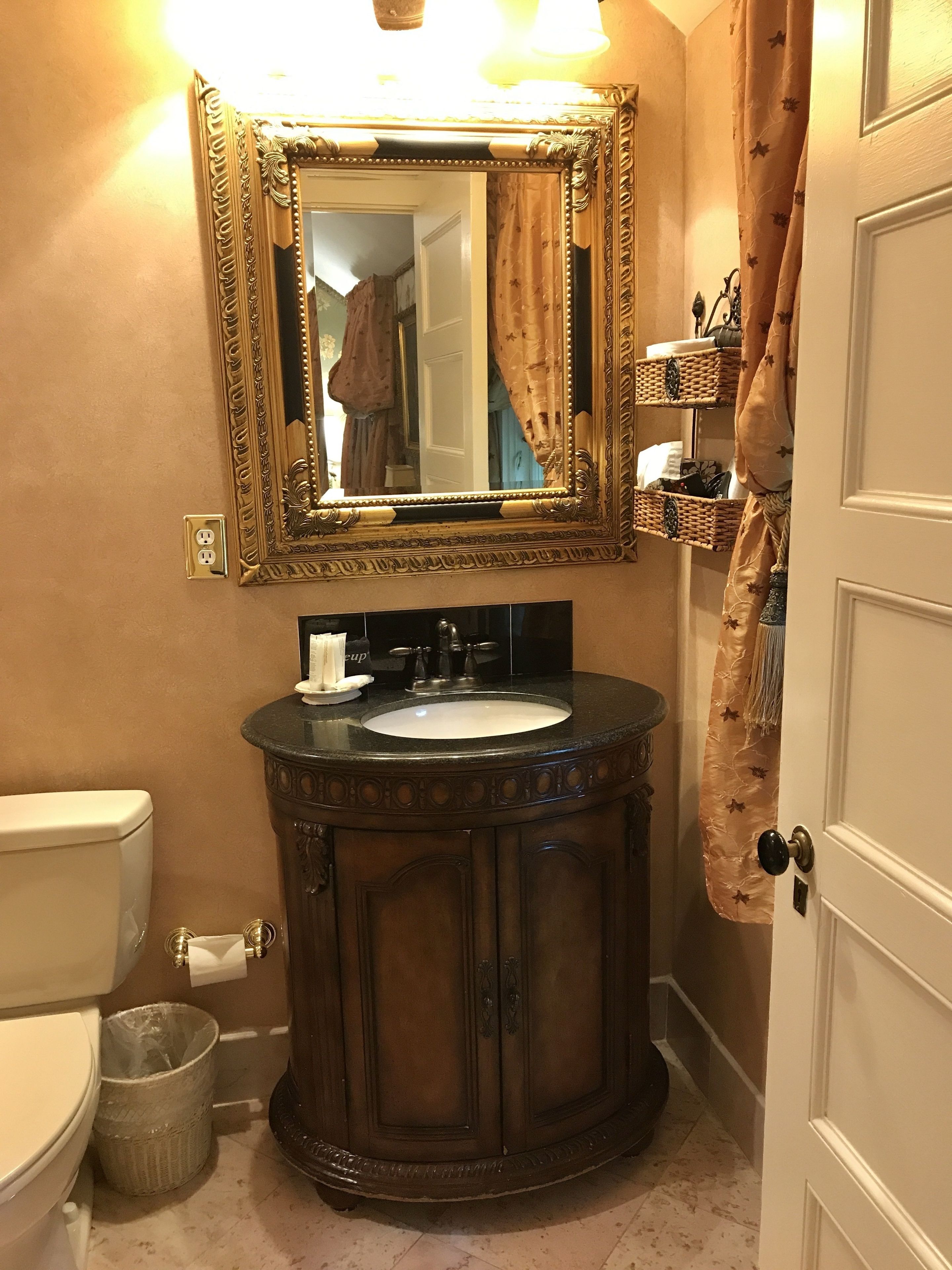 A bathroom with a round vanity, a toilet, a mirror, and a shower curtain.