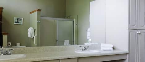 Un baño con un espejo grande, dos lavamanos, un perchero para toallas y un armario.