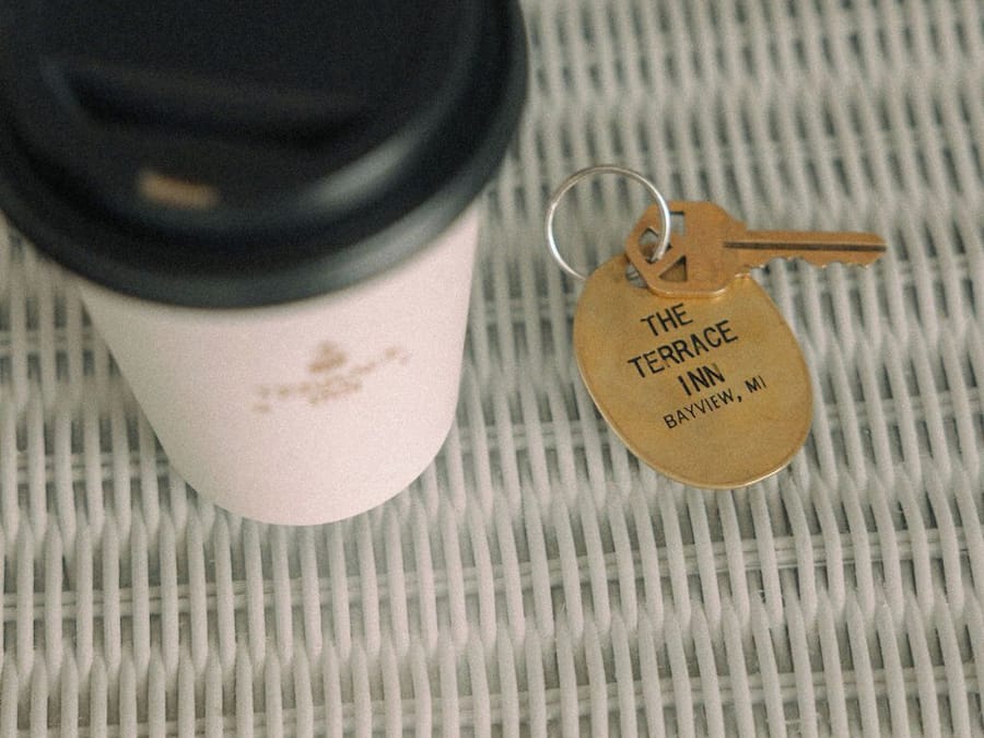 A coffee cup with a black lid and a keychain with a tag that reads "The Terrace Inn Bayview, MI".