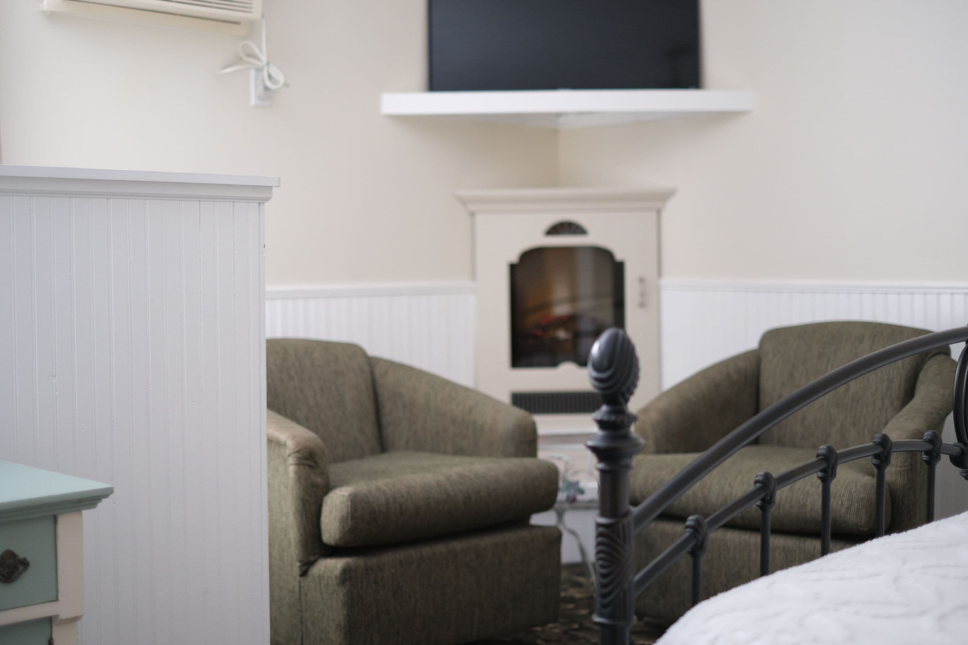 Une chambre à coucher avec un lit, deux fauteuils, une commode et un radiateur.