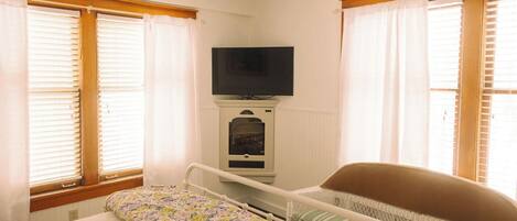 A bedroom with a bed, a television mounted above it, and a radiator below.