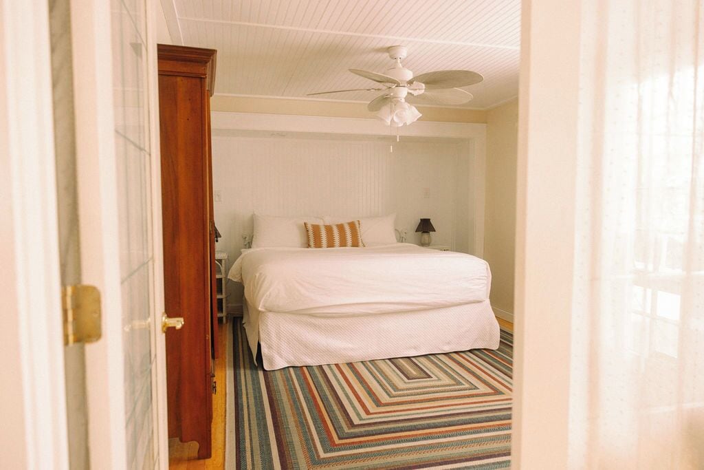 A hotel room with a bed, a ceiling fan, and a patterned carpet.