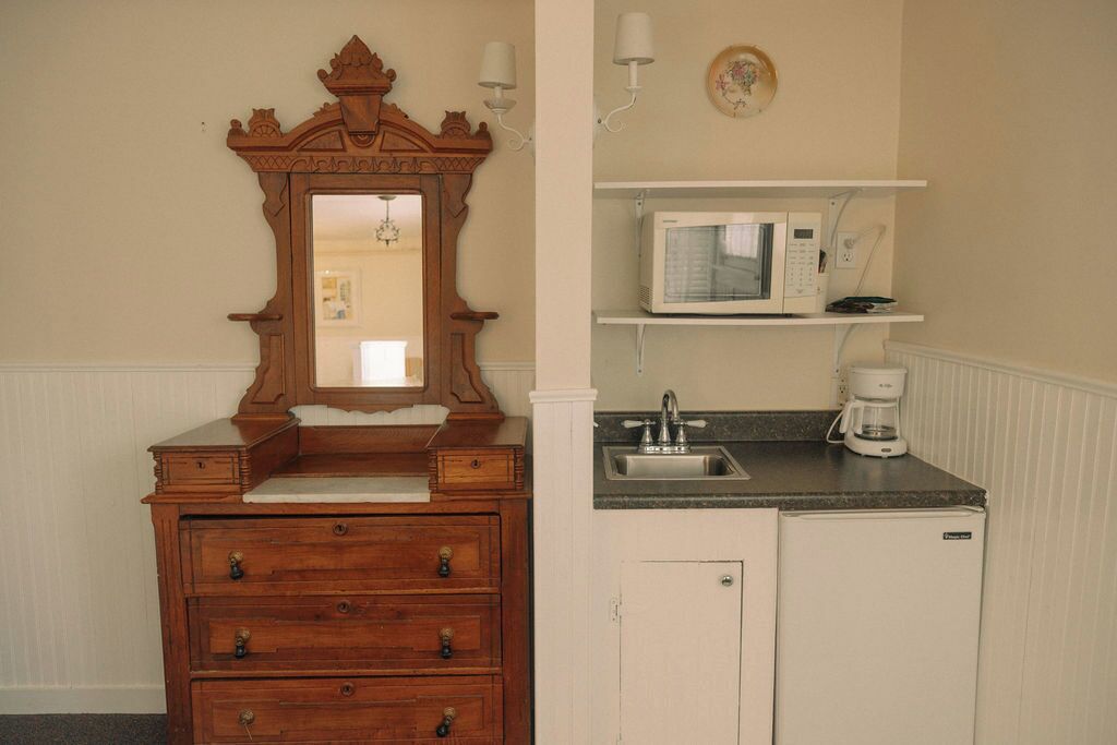 A compact kitchen with a wooden vanity, a microwave, and a coffee maker.