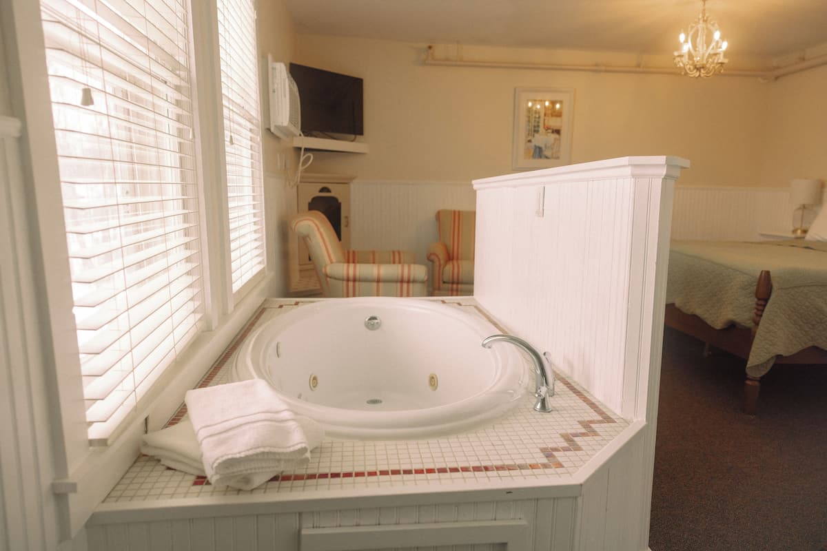A bathroom with a large bathtub, a sink, and a chair.