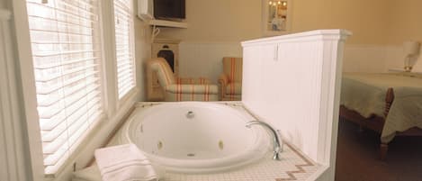 A bathroom with a large bathtub, a sink, and a chair.
