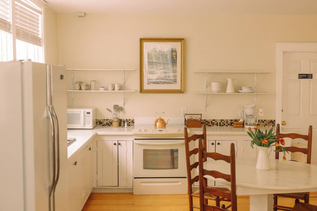 A kitchen with white cabinets, a stove, a microwave, and a dining table with chairs.