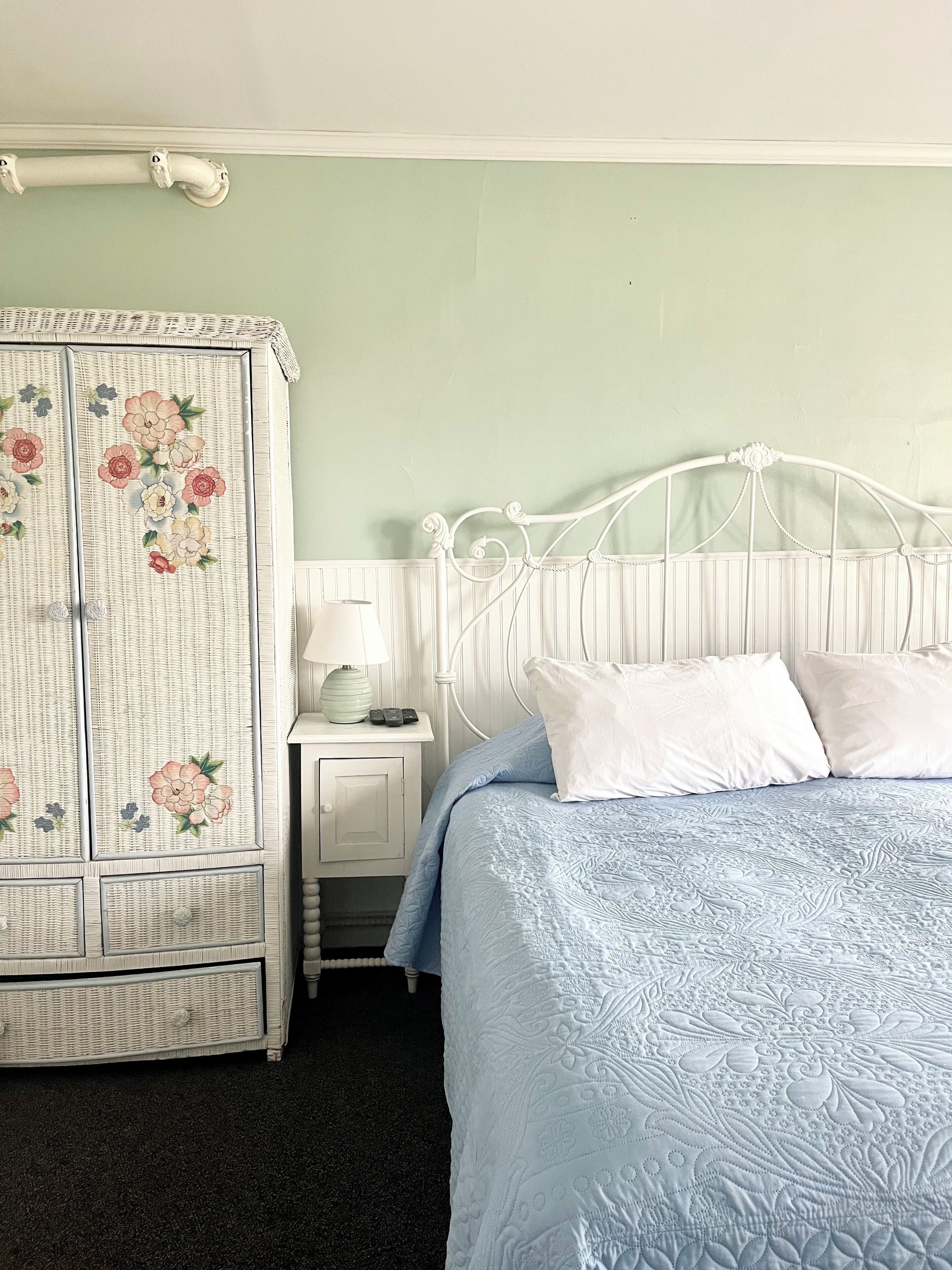 A bedroom with a bed, a nightstand, a lamp, and a wardrobe.