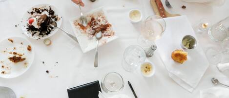 Une table à manger avec des restes de nourriture, des verres à vin et un téléphone intelligent.