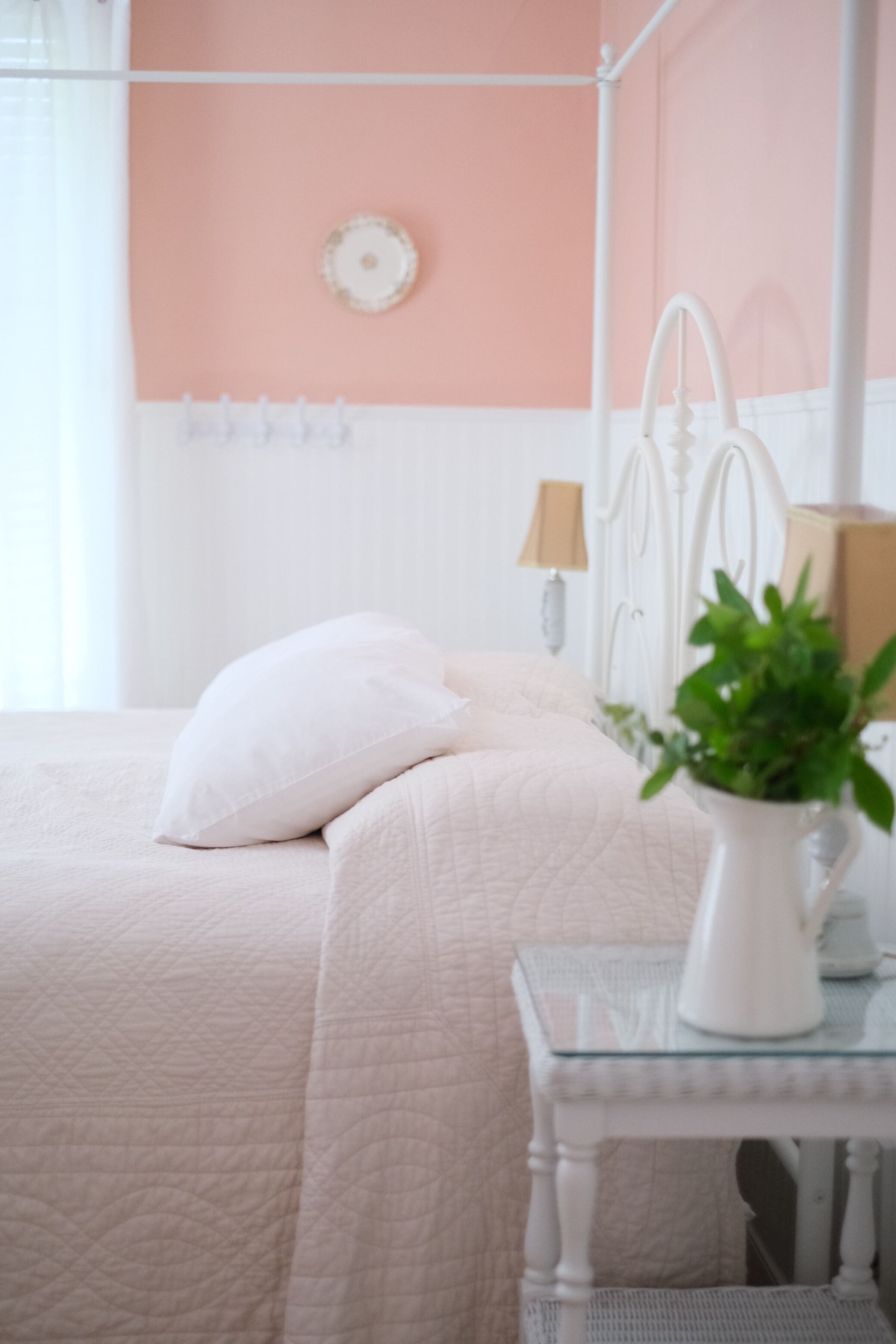 Een keurig opgeruimde slaapkamer met een bed, nachtkastje en wandlamp.