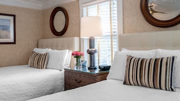A hotel room with two beds, a dresser, a mirror, and a window with blinds.