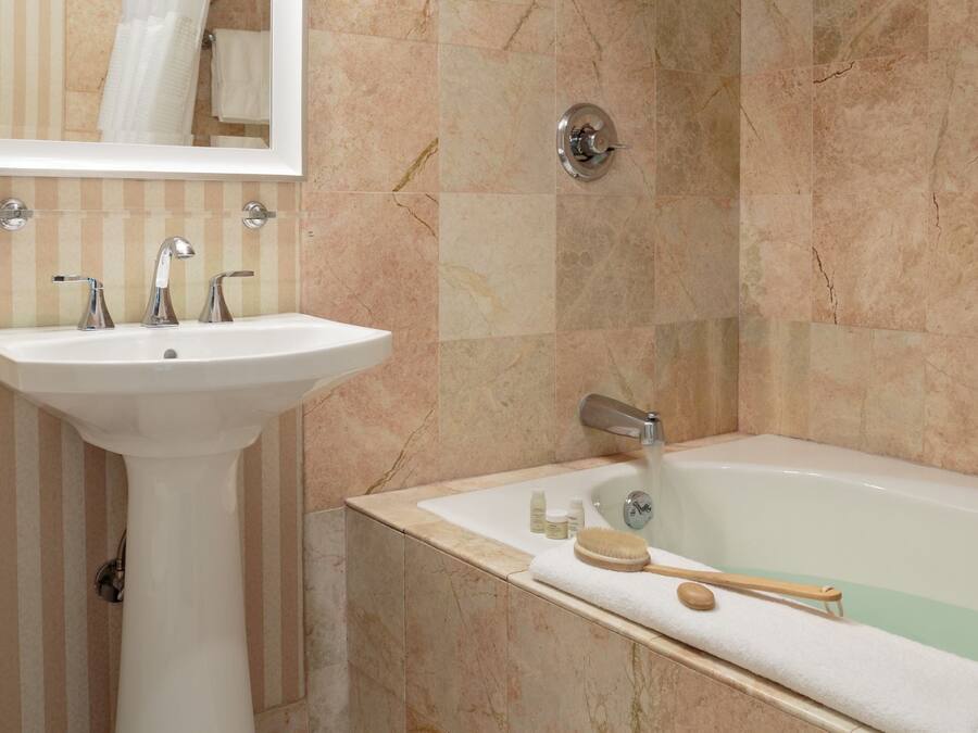 A bathroom with a sink, mirror, and bathtub.