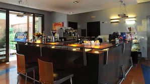 Zona de bar moderna con una barra central, taburetes y una máquina de café.