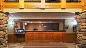 A reception area with a wooden counter, stone walls, and a sign that reads "AmerInn." - AmericInn by Wyndham Rexburg BYUI (Rexburg)