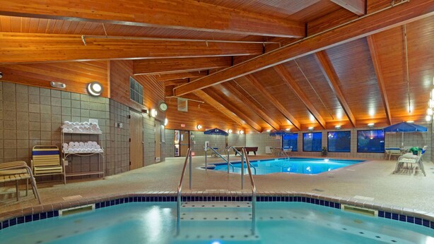 An indoor swimming pool with wooden beams, tiled walls, and a bench area. - AmericInn by Wyndham Rexburg BYUI (Rexburg)