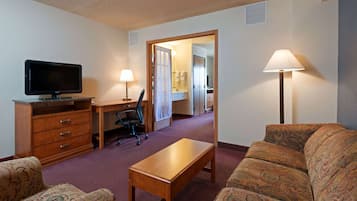 Une chambre d’hôtel équipée d’une télévision, d’un bureau, d’un fauteuil de bureau, d’un canapé et d’une lampe.