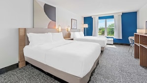 Une chambre d’hôtel avec deux lits, un bureau et une fenêtre avec des rideaux.