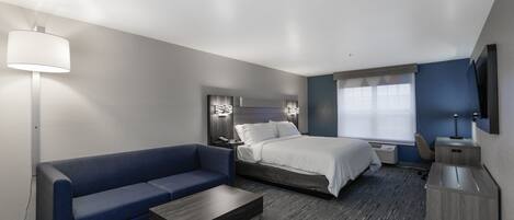 Una habitación de hotel con cama, sofá, escritorio y televisor.