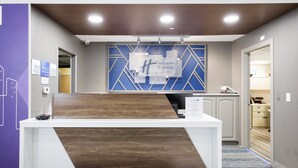 A reception desk with a modern design, a blue and white geometric wall behind it, and a sign indicating it's a Holiday Inn Express Suites location. - Holiday Inn Express & Suites Zion by IHG (Zion)