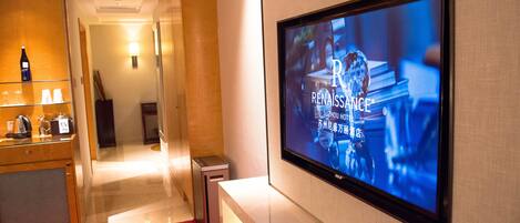 A hotel room with a flat-screen TV mounted on the wall displaying a program.