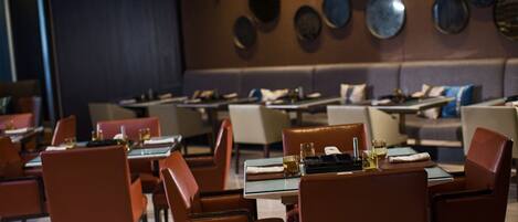 A restaurant with tables set for dining, featuring a modern interior with a mix of seating arrangements.