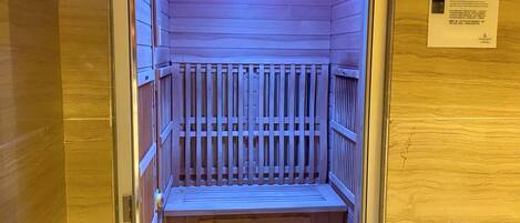 A sauna room with wooden slats and a bench.