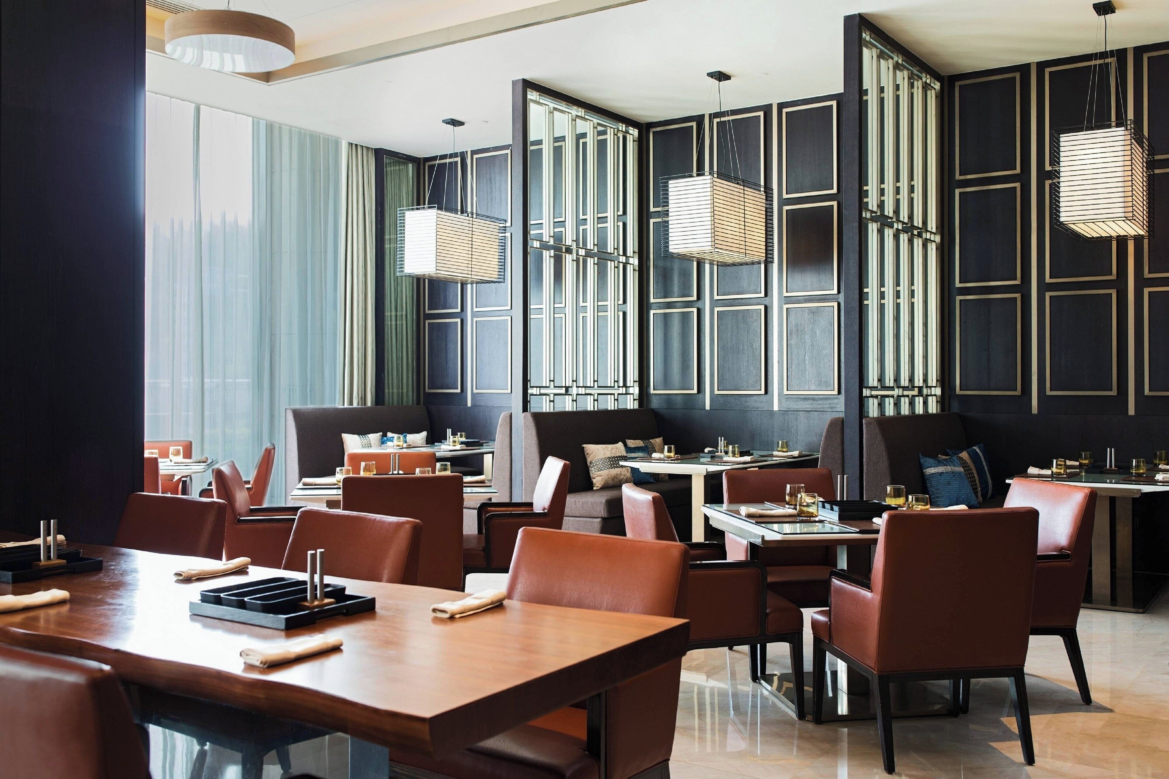 A modern restaurant with high ceilings, large windows, and contemporary furniture.