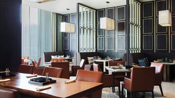 A modern restaurant with high ceilings, large windows, and contemporary furniture.