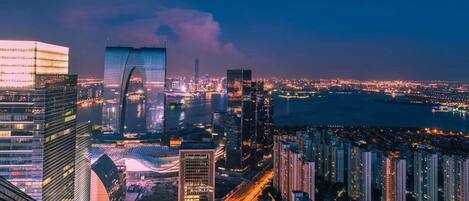 A nighttime cityscape with high-rise buildings and a river.