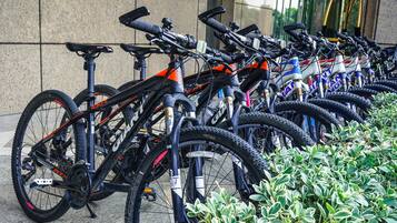 Uma fileira de bicicletas estacionadas encostadas a uma parede de prédio.