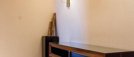 A hallway with a wooden console table, two wall-mounted light fixtures, and a round yellow rug.