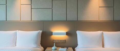 A hotel room with two beds, a nightstand with a lamp, and a wall panel design.