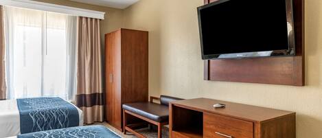 A hotel room with two beds, a desk, a wardrobe, and a TV mounted on the wall.