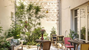 Un patio con mobiliario de mimbre, una banca y una mesa con un jarrón de flores.