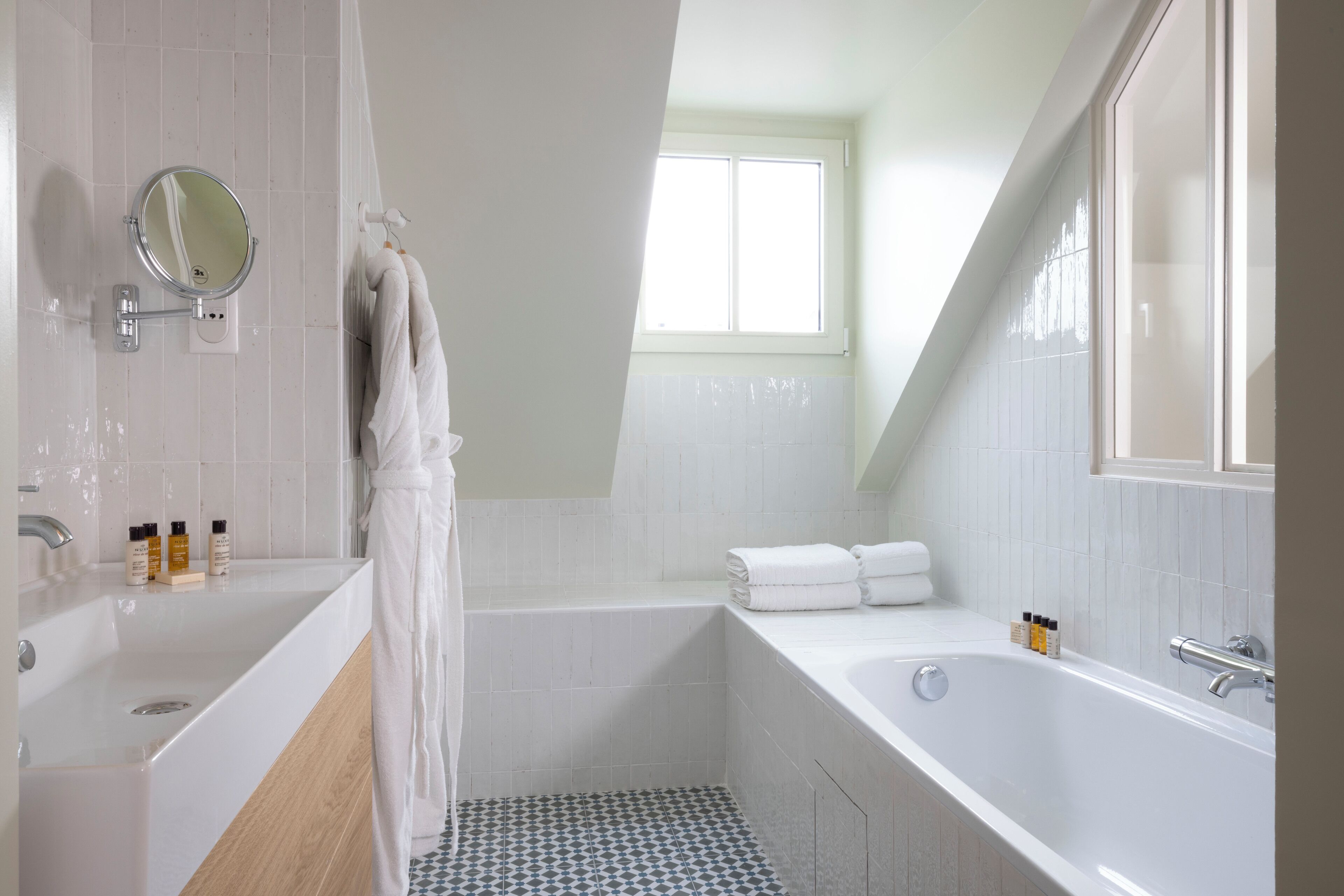 A modern bathroom with a large bathtub, a double sink, and a shower area.