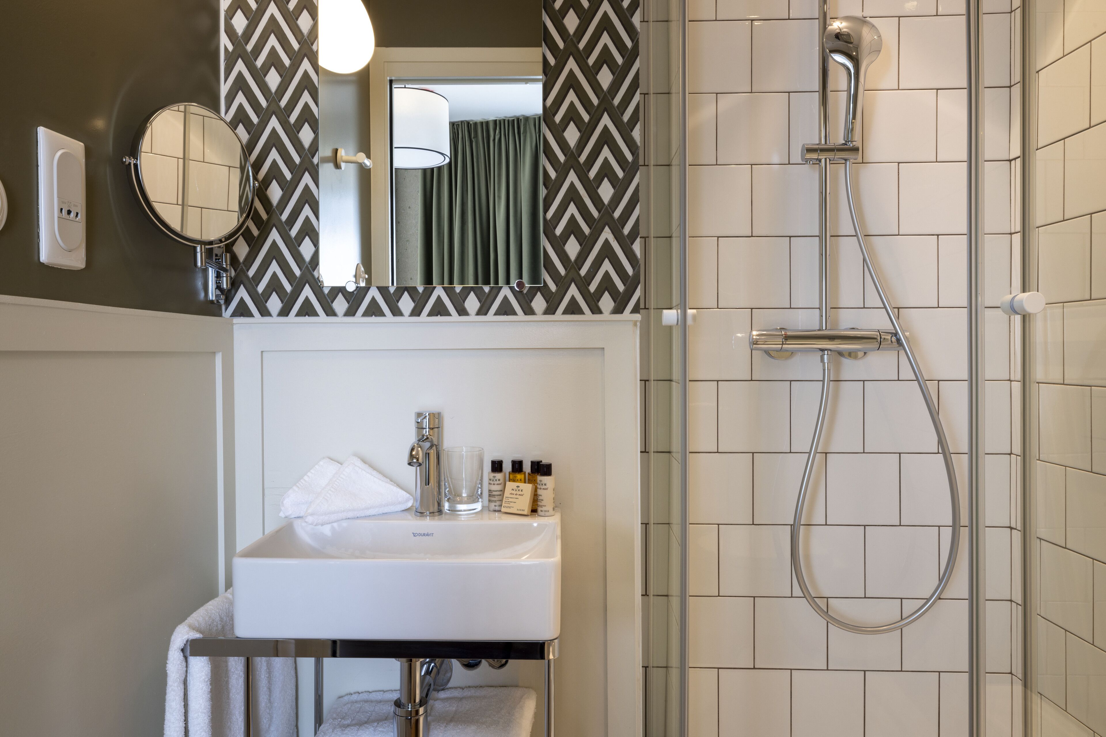 A bathroom with a white sink, mirror, and shower.