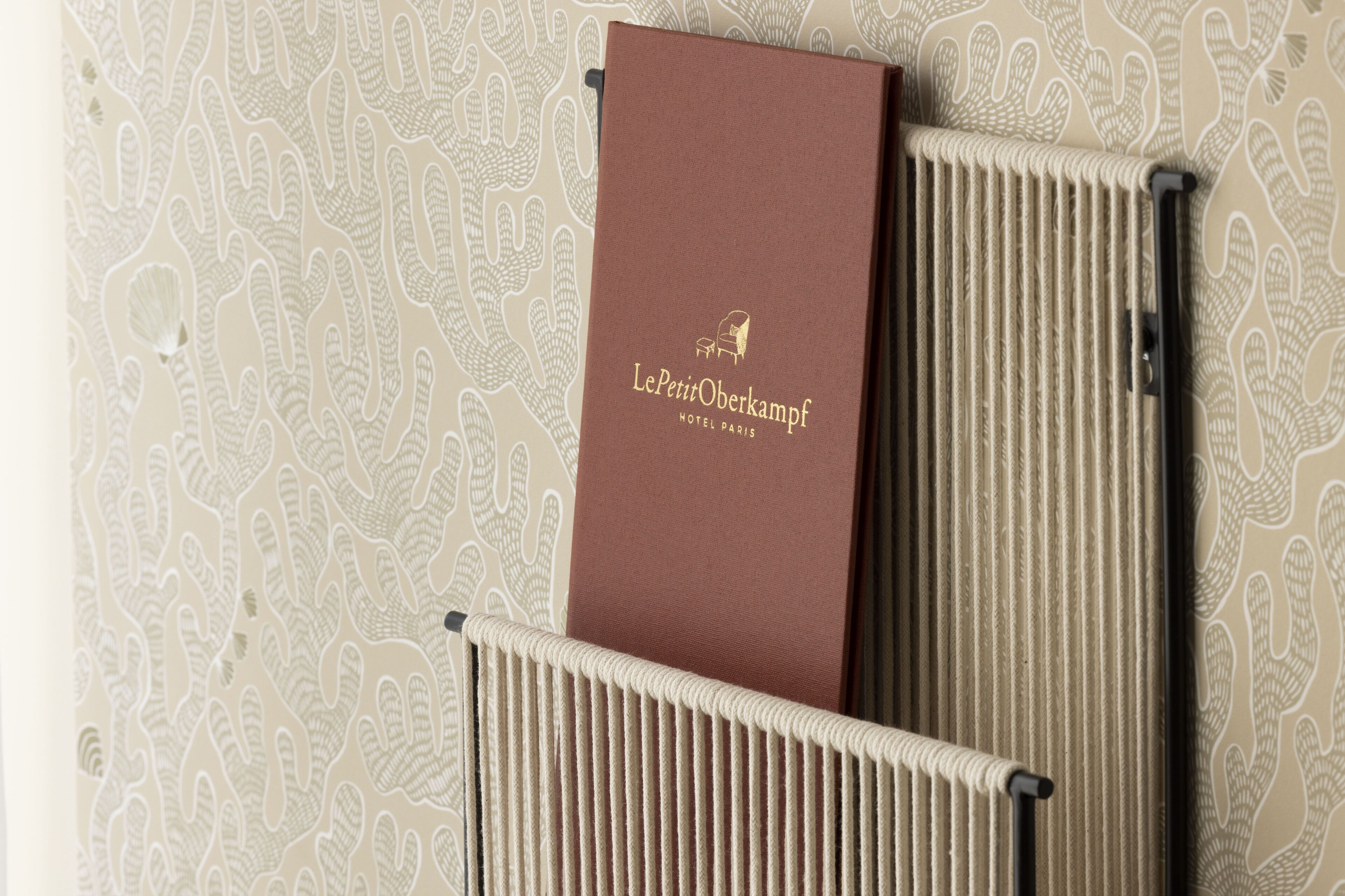 A brown booklet with hotel branding on a textured wall.