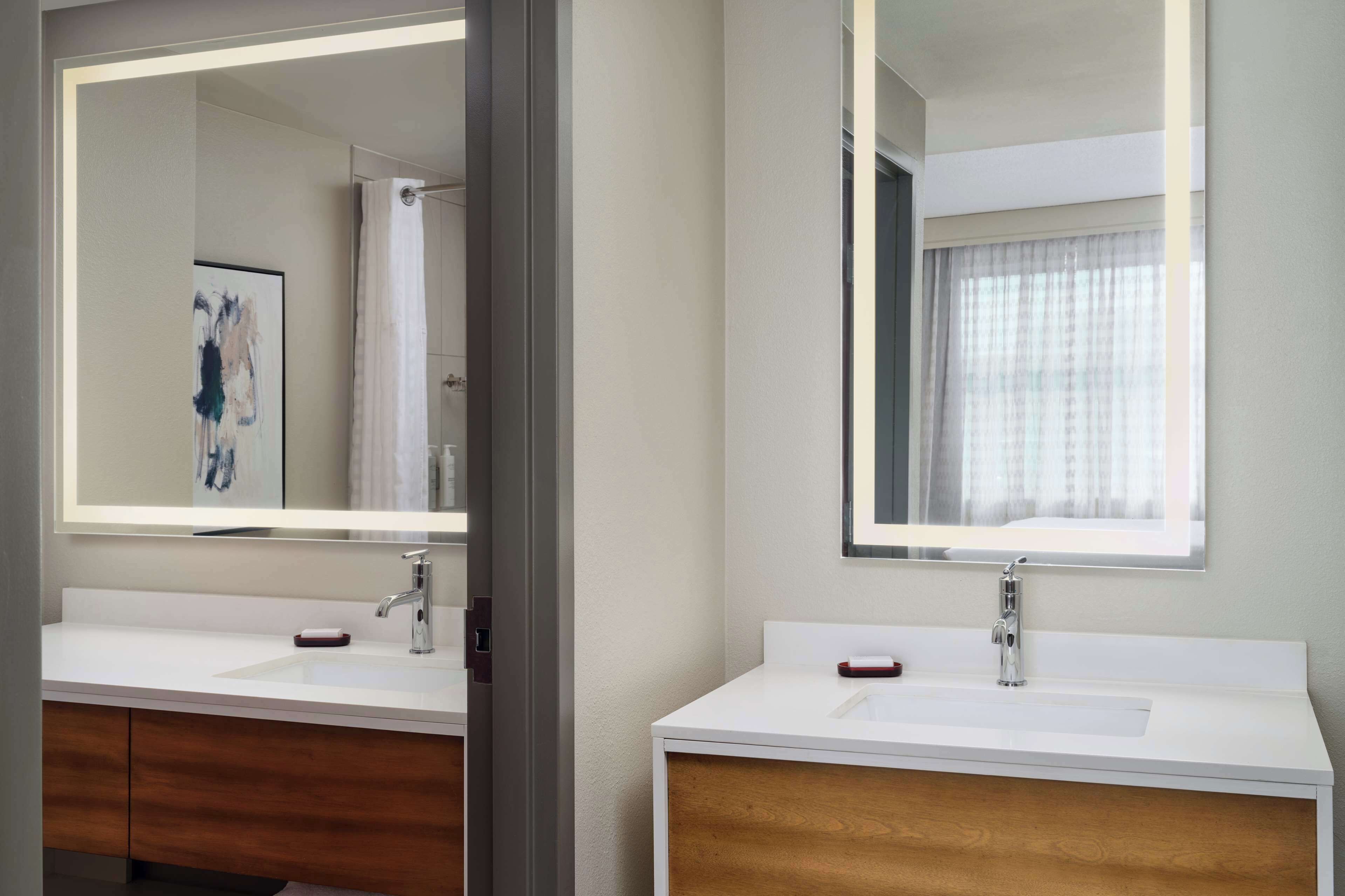 Un baño moderno con dos lavamanos, un espejo grande y un mueble de tocador de madera.