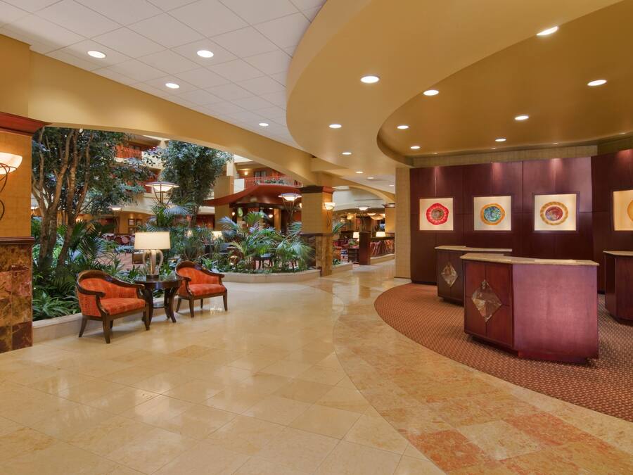 A lobby with a reception desk, seating area, and indoor plants.