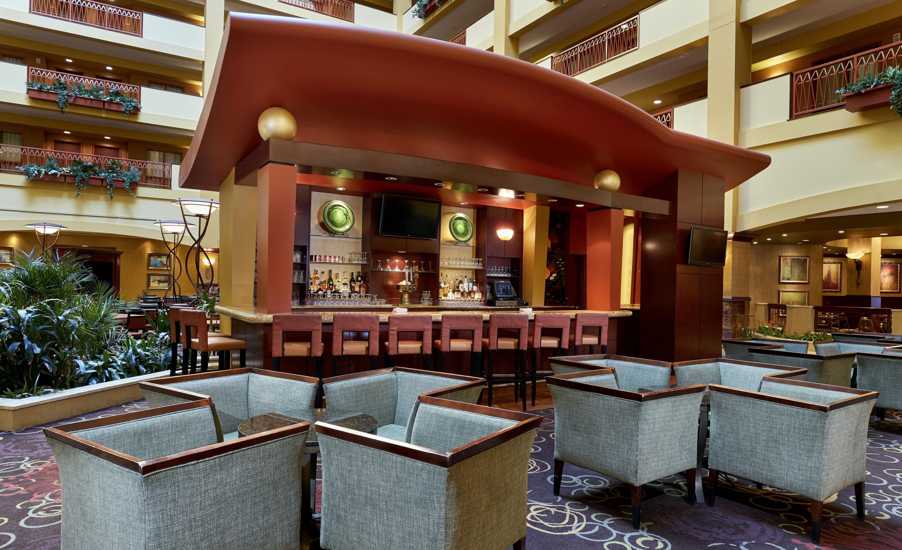 A hotel lobby with a curved bar area, seating, and a view of the upper floors.