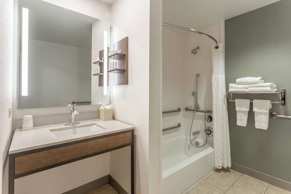 A modern bathroom with a sink, mirror, and shower area.