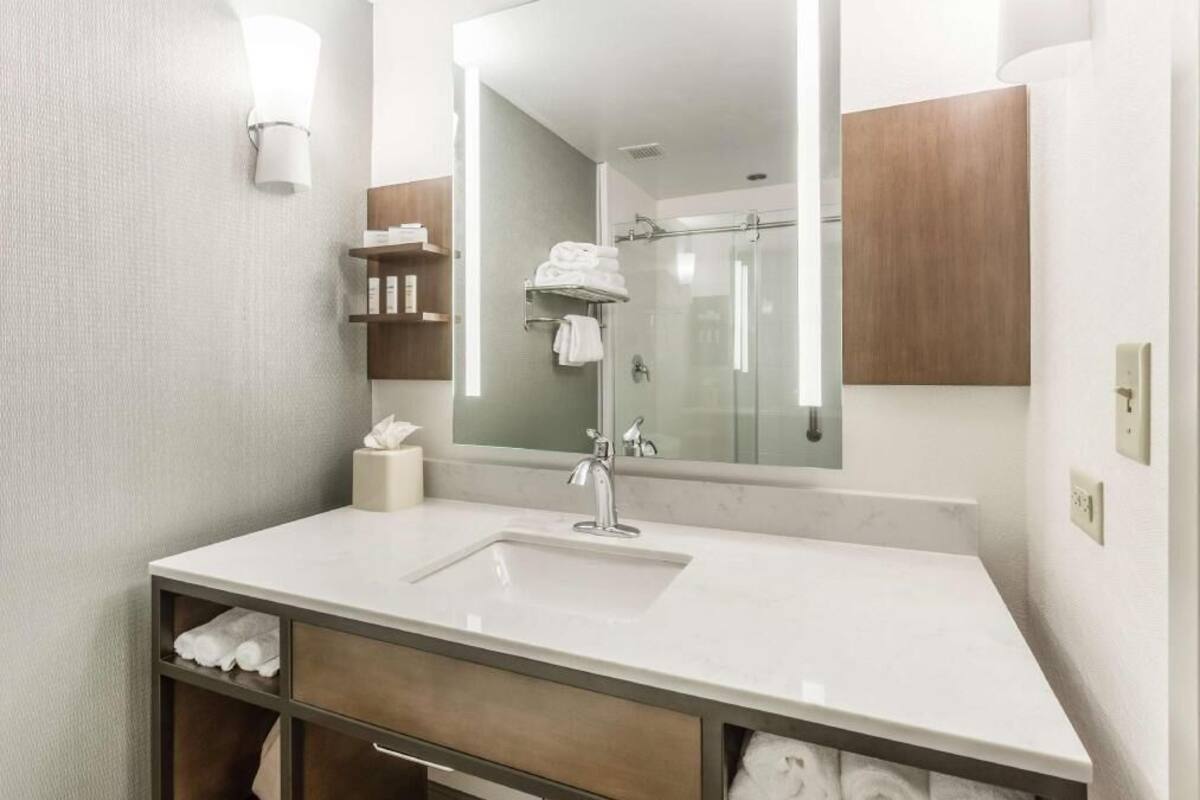 Een moderne badkamer met een grote spiegel, een wastafel en een douche.