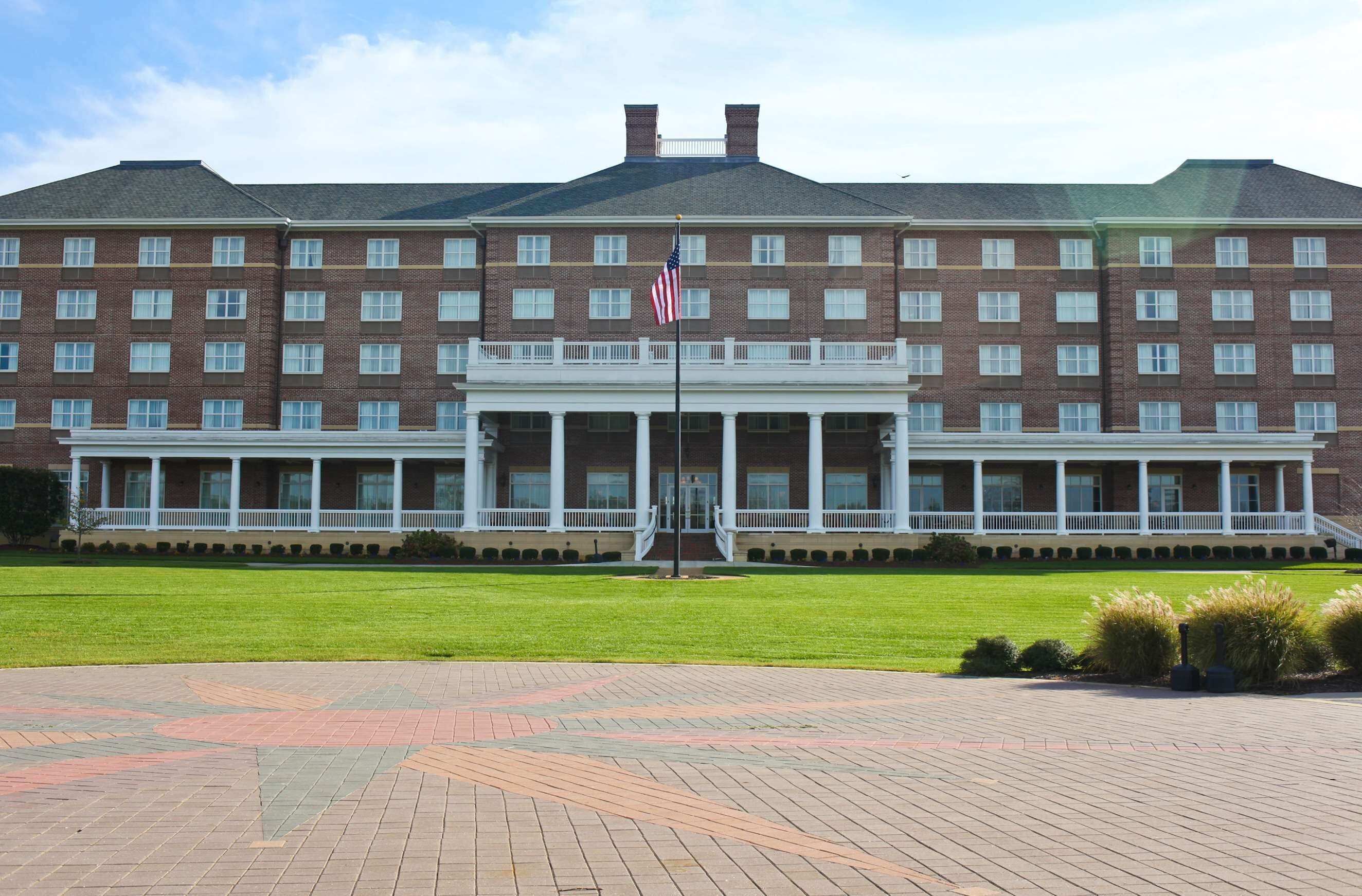 A large brick building with a central entrance and a flagpole.