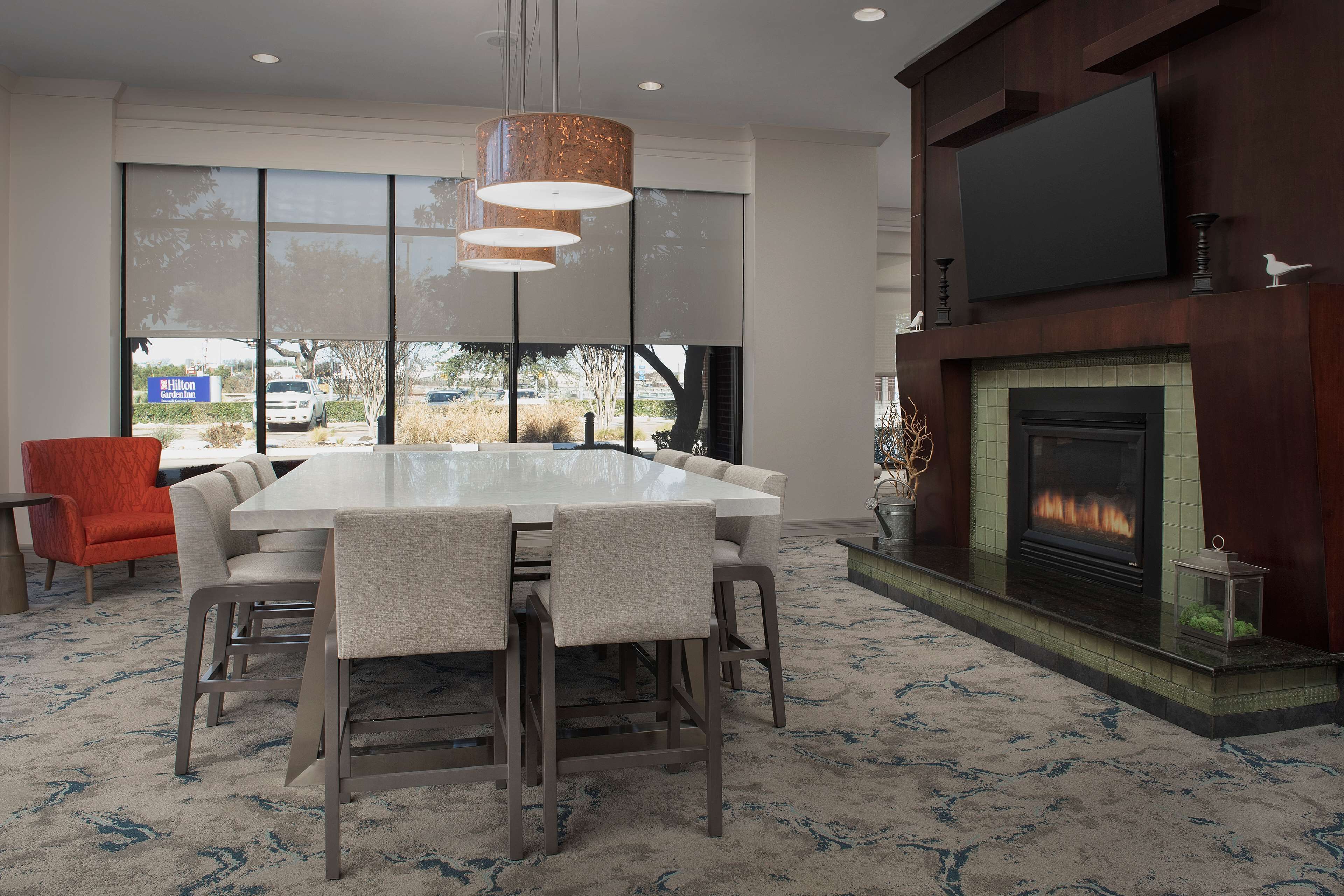 A modern dining area with a large table, chairs, a fireplace, and a TV mounted on the wall.