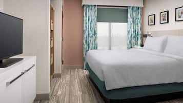 Una habitación de hotel con cama, televisión, armario y ventana con cortinas.