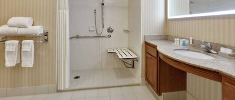 A modern bathroom with a walk-in shower, a vanity with a sink, and a mirror.