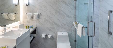 A modern bathroom with a glass-enclosed shower, a white toilet, and a vanity with a mirror and towel rack.