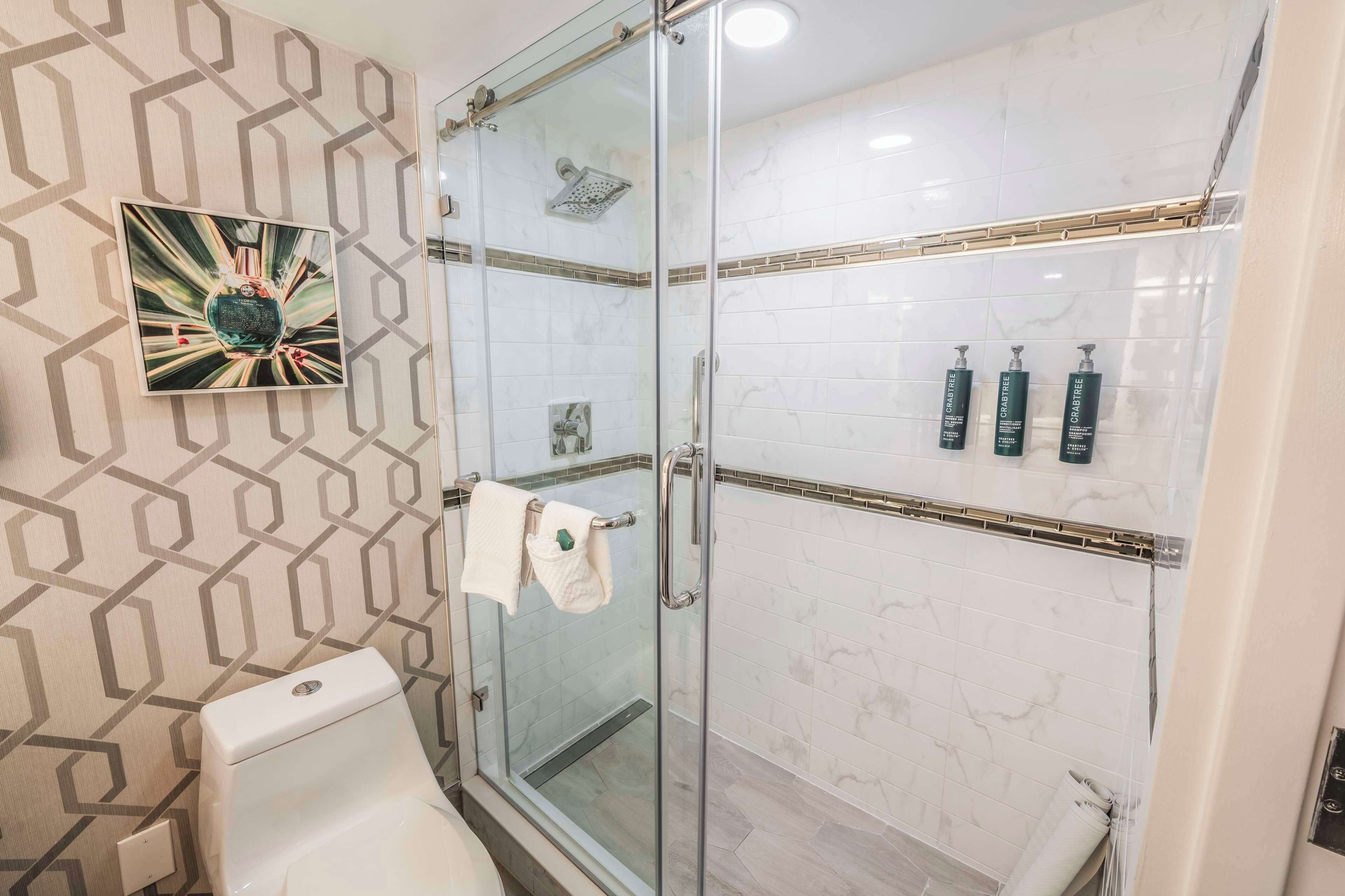 A modern bathroom with a glass shower enclosure, a toilet, and a towel rack.